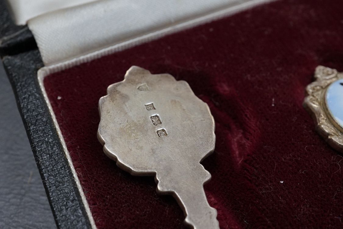 A cased set of six Elizabeth II silver teaspoons, the enamelled terminals decorated with a jockey in racing colours, maker JJW, Birmingham, 1978, together with a cased set of five (ex six) silver teaspoons and a cased se